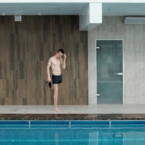 Amputee athlete preparing at an indoor swimming pool, portraying determination and fitness.