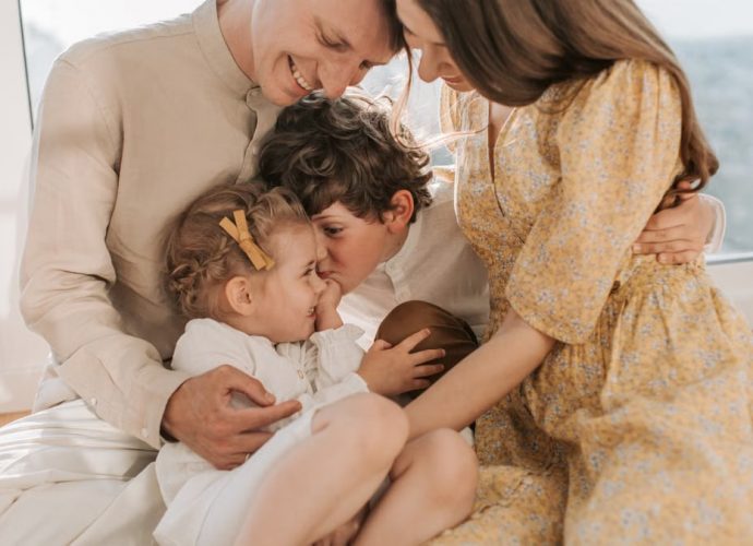 A happy family of four sitting together and sharing a loving moment indoors.