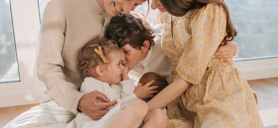 A happy family of four sitting together and sharing a loving moment indoors.